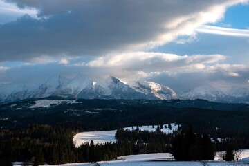 Majestic snow mountains rise under a cloudy sky. Rzepiska, High Tatras, Poland