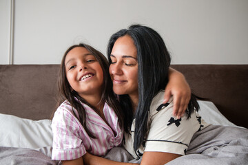 A woman and a child are hugging each other on a bed