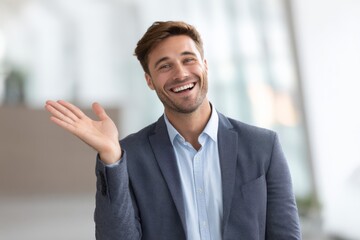 Fototapeta premium A cheerful businessman smiles warmly with open hands, showing friendliness and approachability in conversation.