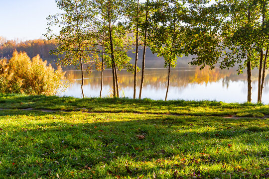 Sunny autumn in the park. Autumn landscape with colourful trees and reflections in the pond. Katowice, Silesia, Poland