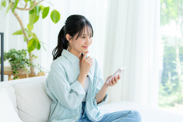 Obraz premium 部屋でスマホを操作する若い女性