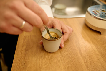 Hand stirring freshly brewed coffee in small cup