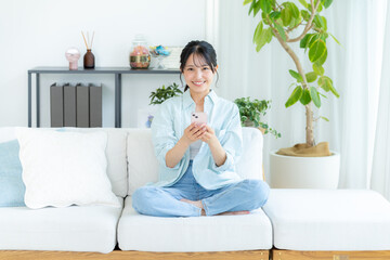 部屋でスマホを操作する若い女性