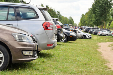 A large temporary parking lot for cars on a green grass field
