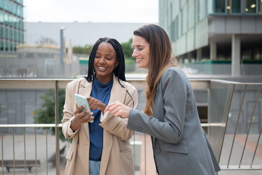 Diverse business women smiling and sharing smartphone screen