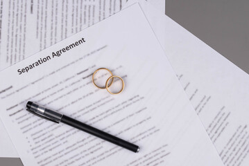 Marital Settlement Separation Agreement paper document with wedding rings on table, ready for signature, symbolizing divorce, prenuptial contract, breakup, and separation.