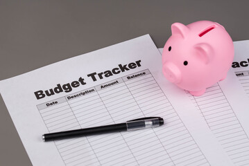 Open daily planner notebook on desk, with organized Monthly Budget tracking table and Piggy bank. With dates, categories and expenses. Personal finance management, spending and budgeting habits concep