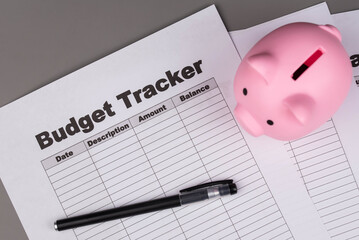 Open daily planner notebook on desk, with organized Monthly Budget tracking table and Piggy bank. With dates, categories and expenses. Personal finance management, spending and budgeting habits concep