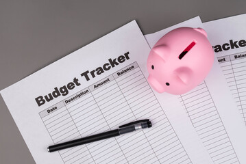 Open daily planner notebook on desk, with organized Monthly Budget tracking table and Piggy bank. With dates, categories and expenses. Personal finance management, spending and budgeting habits concep