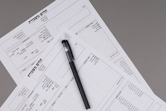 Israeli salary payslips (tlush maskoret in Hebrew) on desk, symbolizing payroll, income, taxes, and financial accounting concept.