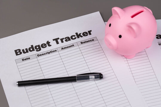 Open daily planner notebook on desk, with organized Monthly Budget tracking table and Piggy bank. With dates, categories and expenses. Personal finance management, spending and budgeting habits concep