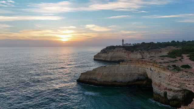 Algarve lighthouse on coastal cliffs at sunset, Portugal