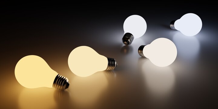 Light bulbs laying on the floor showing different color temperatures from warm orange to cool blue on dark background