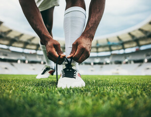 Young football player tying shoelaces on a grass field before a match