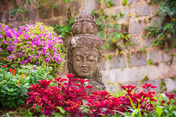 Stone Buddha statue in garden among flowers