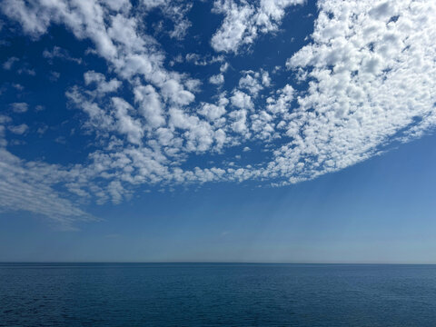 Puffy white clouds over calm blue sea.