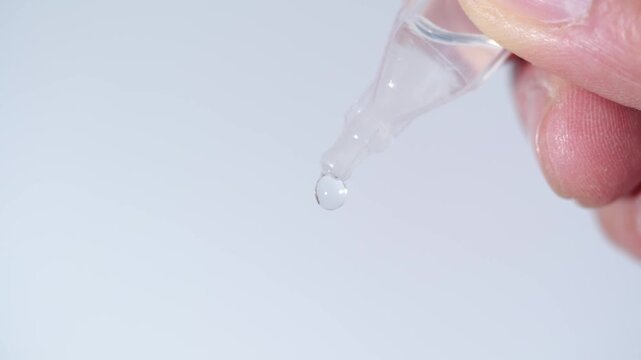 Close-up of a disposable eye drop vial administering a clear liquid solution into a person's open eye for hydration or medical treatment.