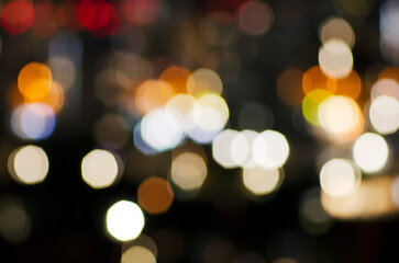 A blurred city street image at night. Abstract blur urban city street road with lighting bokeh for background. There is noise in the photo due to lack of light.