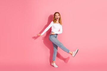 Young cheerful woman posing in casual fashion style against a pink background with a playful...