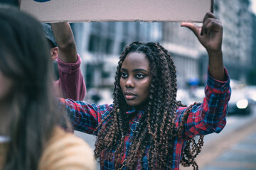 Young woman participates in protest holding a sign in a busy city street during the day