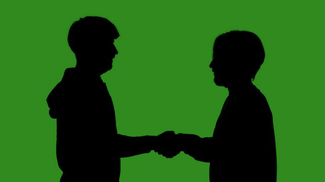 Black silhouettes of two men greet each other with a high five against a green chroma key background. Minimalist contrast and modern visual composition, mockup.