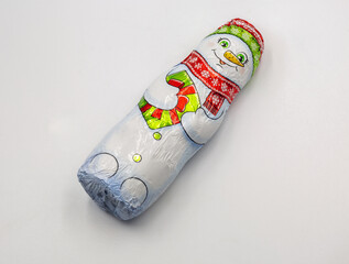 Chocolate snowman wrapped in festive foil packaging closeup on white.