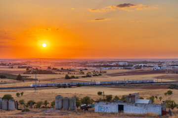 High speed train traveling Alcazar de San Juan at sunset