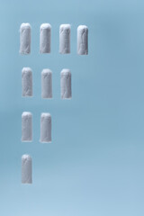 Feminine hygiene products, tampons floating on blue background for woman’s health, period care, medical advertising and personal wellness banner concepts 