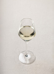 Glass of white wine on neutral linen background
