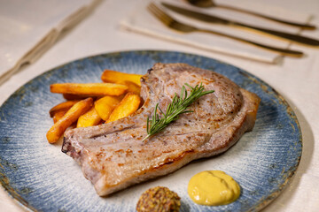 Grilled pork chop with french fries and mustard