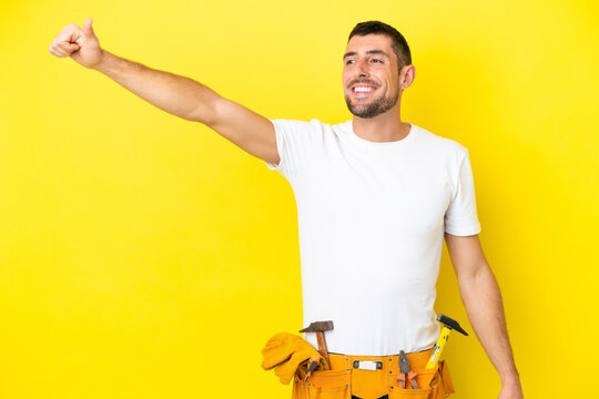 young electrician caucasian man isolated on yellow background giving a thumbs up gesture