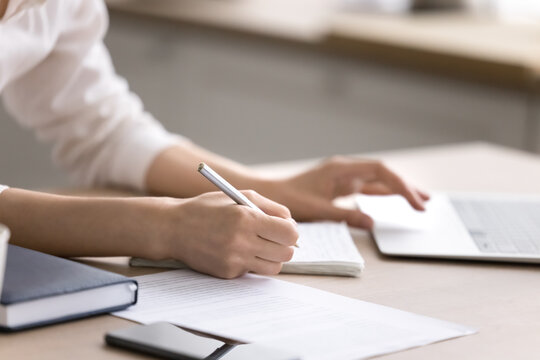 Closeup female hands writing in copybook checking notebook paper documents
