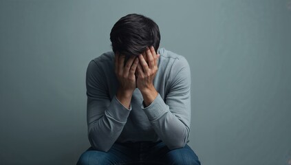 Depressed man covering his face with hands expressing sadness and grief, seeking help for mental health and emotional wellbeing