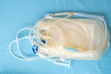 Close up of empty plasma collection bags with medical tubes and connectors on a blue background, used for blood donation transfusion or laboratory healthcare purposes in clinical environment. top view