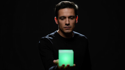 Man holding a glowing cube in his hand against a dark background.