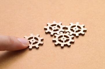 Integrating the Final Piece: A finger nudges a wooden cog into place, symbolizing the completion of a system and finding the 