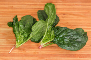 Fresh spinach stems with dark green leaves on cutting board