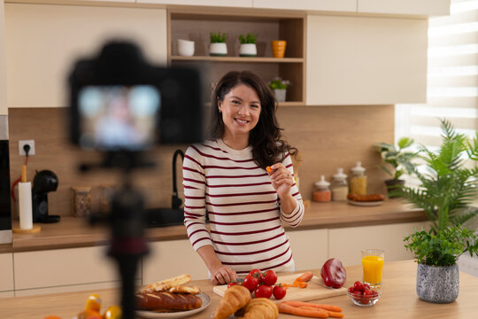 Woman vlogging about cooking healthy food in kitchen