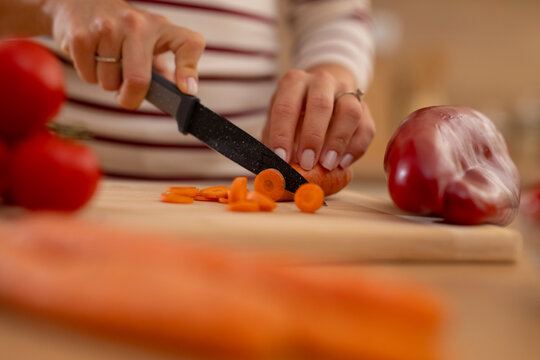 Woman slicing carrot for healthy food preparation