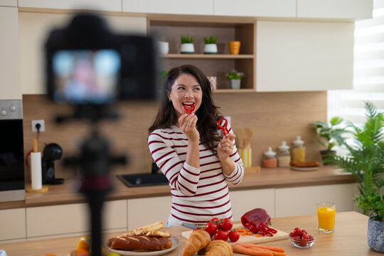 Woman vlogging cooking showing red pepper in kitchen