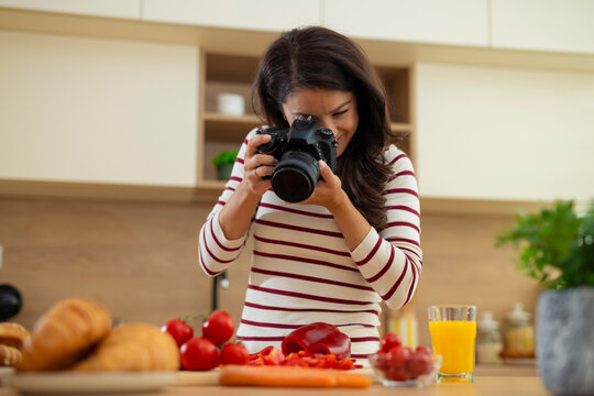 Woman photographing healthy food in modern kitchen