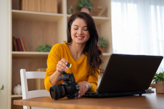 Woman photographer uploading images from camera to laptop