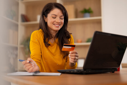 Woman shopping online using credit card and laptop at home