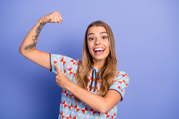 Energetic young woman with tattoo flexing her arm and pointing to it while smiling in a colorful...