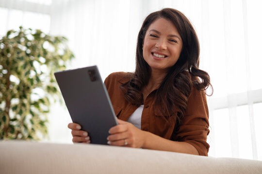 Woman smiling while using tablet for connectivity at home