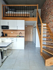 kitchen and living area with wooden staircase and cozy loft sleeping area in a contemporary urban apartment