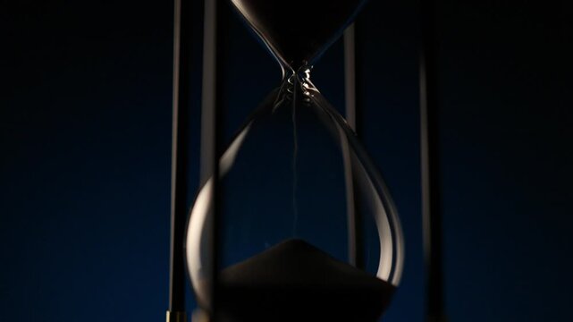 macro shot of sand flowing inside a transparent hourglass, illustrating balance, decay, and the eternal rhythm of time