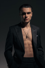 Obraz premium sexy shirtless man in black tuxedo holding hands in pockets and looking forward