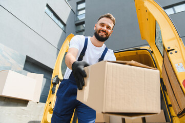 Delivery man holding cardboard box next to van