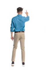 Back view of casual man standing and pointing up